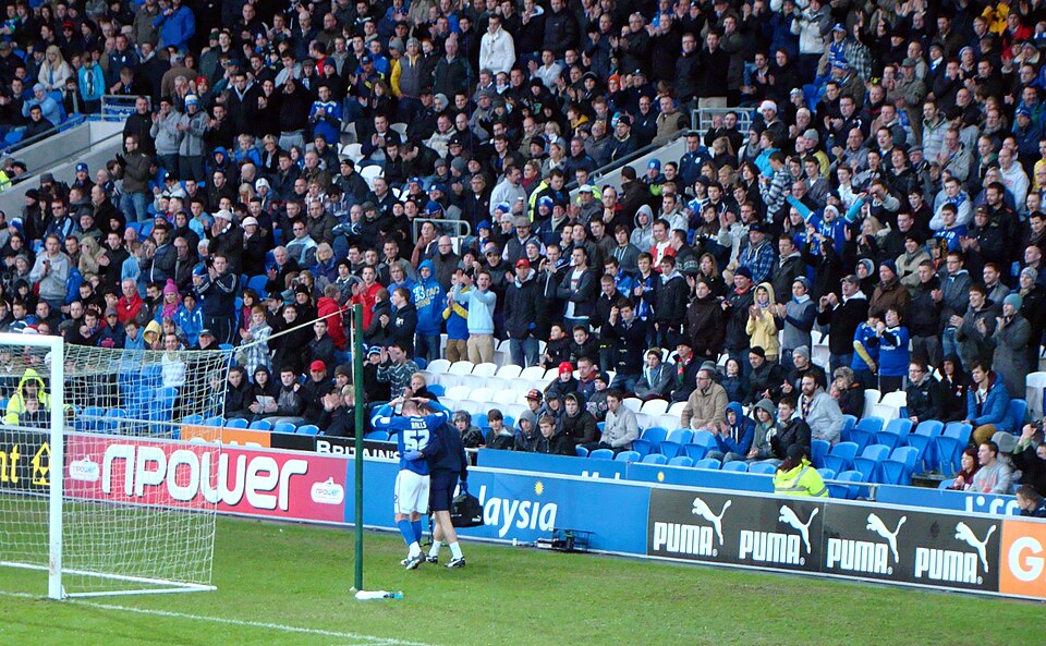 Aficionados viendo un partido de fútbol y revisando cuotas en pantalla