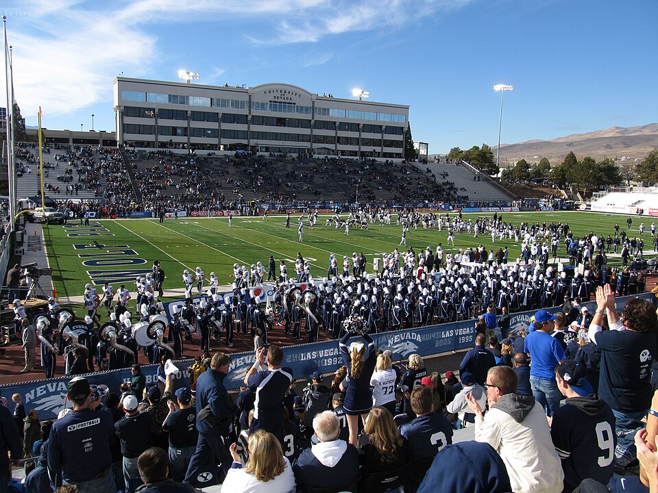 Hinchas siguiendo un partido nocturno con tensión en la tribuna